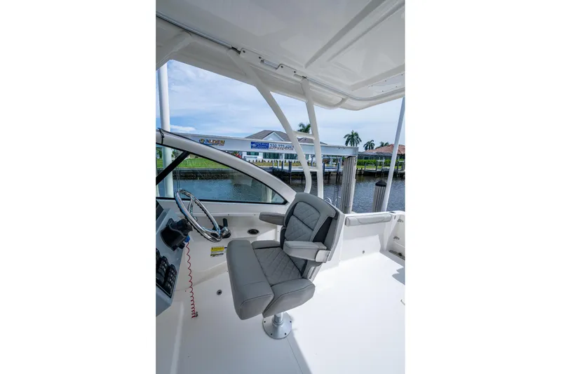 Slide: The Image of 2022 Pursuit DC 246 Dual Console boat interior with helm seat and steering wheel. - 22