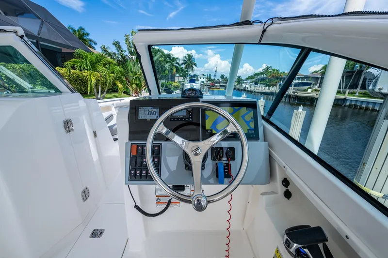 Slide: The Image of 2022 Pursuit DC 246 Dual Console boat helm with steering wheel and navigation display. - 24