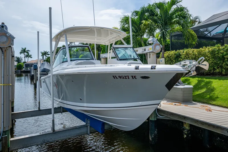 Slide: The Image of 2022 Pursuit DC 246 Dual Console boat docked near lush greenery and waterway. - 3