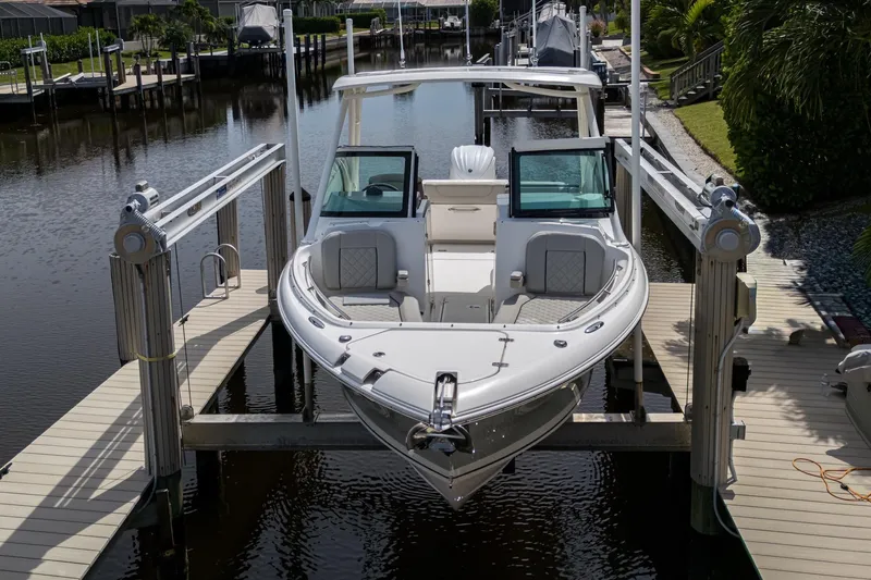 Slide: The Image of 2022 Pursuit DC 246 Dual Console boat docked on a lift in a marina. - 30
