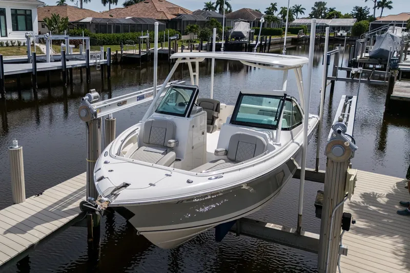 Slide: The Image of 2022 Pursuit DC 246 Dual Console boat docked in a scenic marina setting. - 31