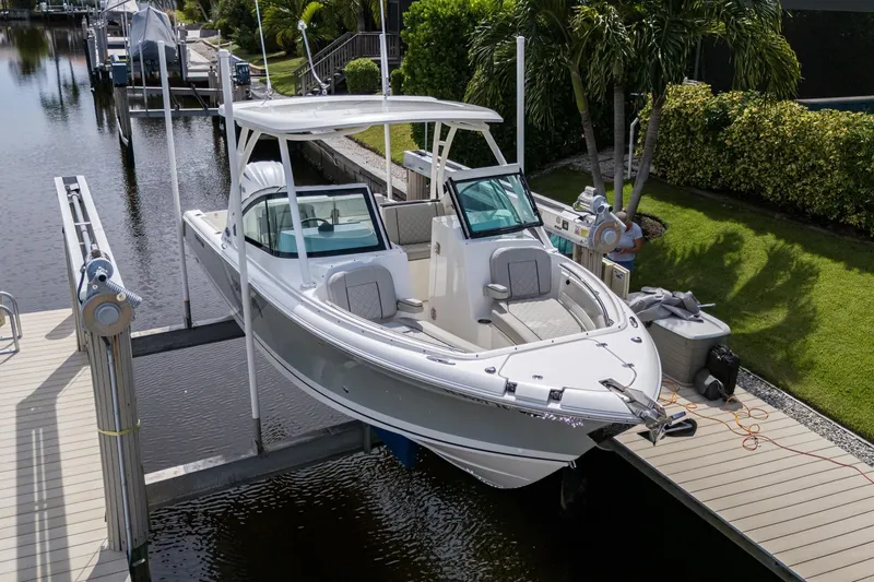 Slide: The Image of 2022 Pursuit DC 246 Dual Console boat docked on a lift by a canal. - 32