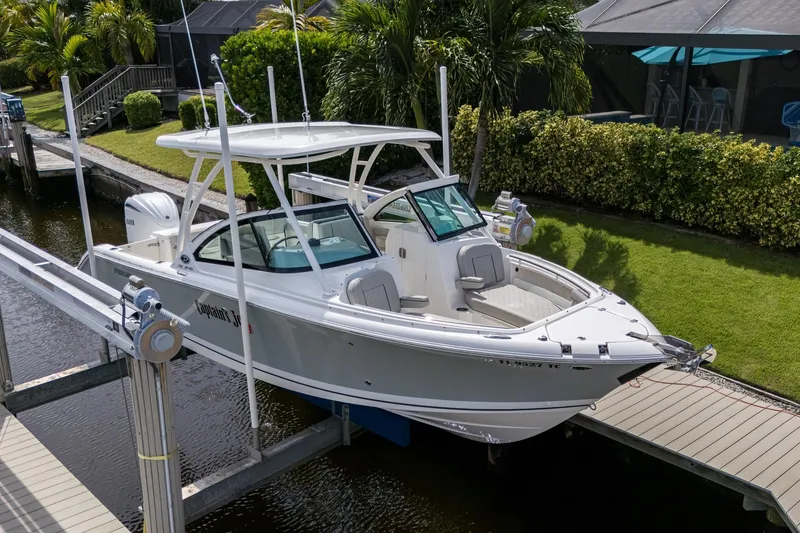 Slide: The Image of 2022 Pursuit DC 246 Dual Console boat docked near lush greenery. - 34