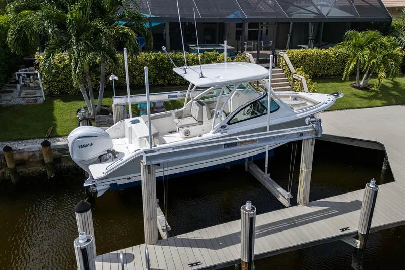 Slide: The Image of 2022 Pursuit DC 246 Dual Console boat docked on lift near waterfront home. - 37