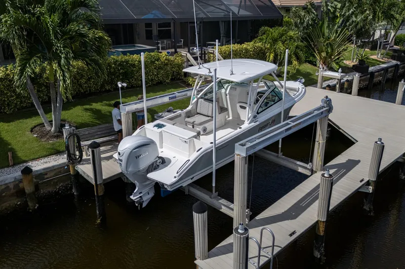 Slide: The Image of 2022 Pursuit DC 246 Dual Console boat docked on a lift by a waterfront home. - 38