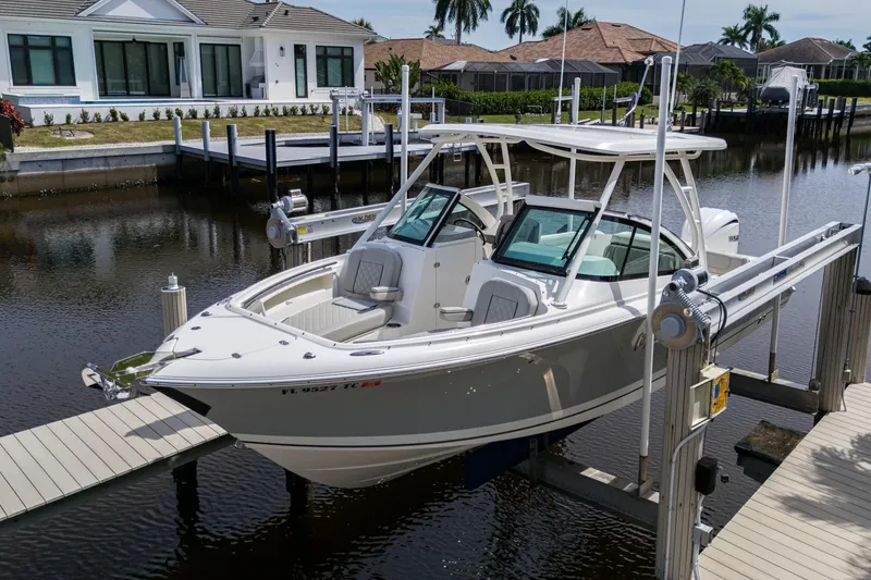 Slide: The Image of 2022 Pursuit DC 246 Dual Console boat docked near waterfront homes. - 5