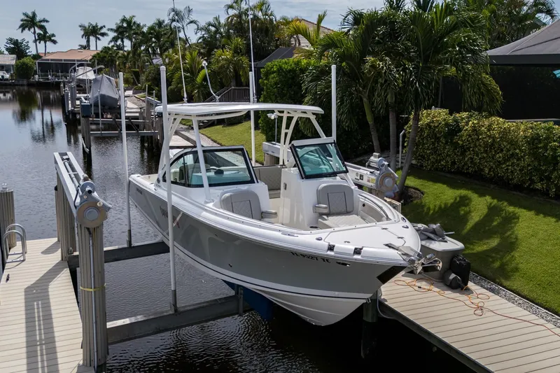 Slide: The Image of 2022 Pursuit DC 246 Dual Console boat docked near lush greenery and calm waters. - 7