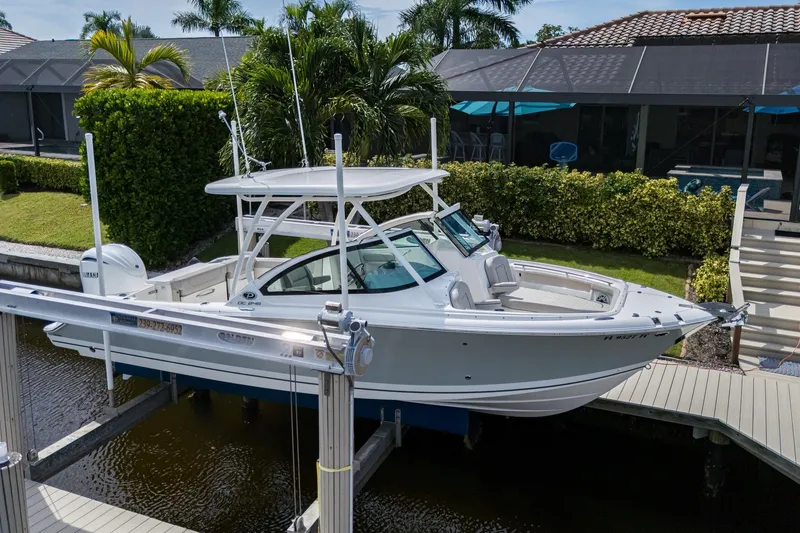 Slide: The Image of 2022 Pursuit DC 246 Dual Console boat docked near a waterfront home. - 8