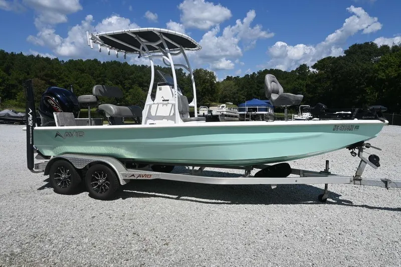 Slide: The Image of Avid 21 Mag 2025 boat on trailer, light blue hull, parked outdoors. - 0