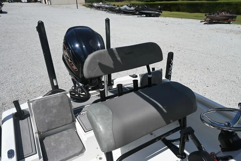Slide: The Image of Avid 21 Mag 2025 boat interior with seating and motor, parked on gravel near water. - 12
