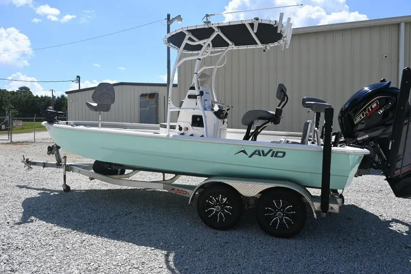 Slide: The Image of 2025 Avid 21 Mag boat on trailer, light blue hull, parked outdoors. - 2