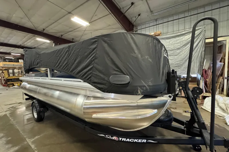 Slide: The Image of 2025 Sun Tracker Bass Buggy 18 DLX pontoon boat with cover in a warehouse. - 13