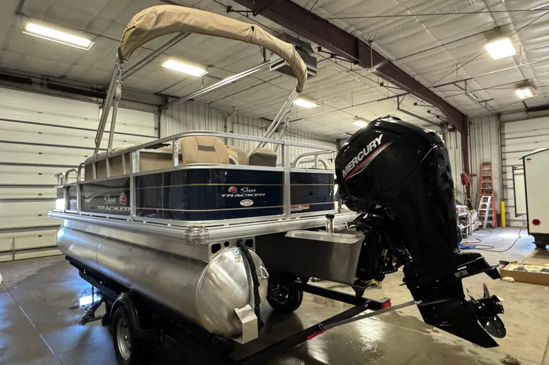 Slide: The Image of 2025 Sun Tracker Bass Buggy 18 DLX pontoon boat with Mercury engine in a garage. - 4