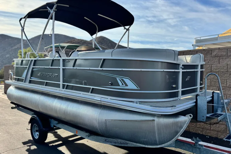 Slide: The Image of 2019 Starcraft EX 20 C pontoon boat on trailer, parked outdoors. - 1