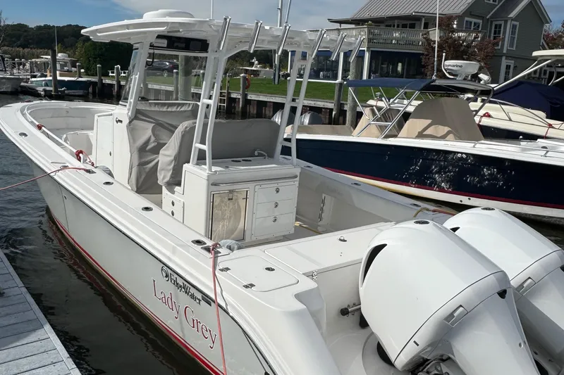Slide: The Image of 2016 Edgewater 320CC boat docked, featuring dual outboard engines and spacious deck. - 4