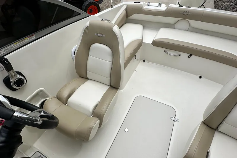 Slide: The Image of 2019 Stingray 191 DC boat interior with beige and white seating, steering wheel, and storage compartment. - 12