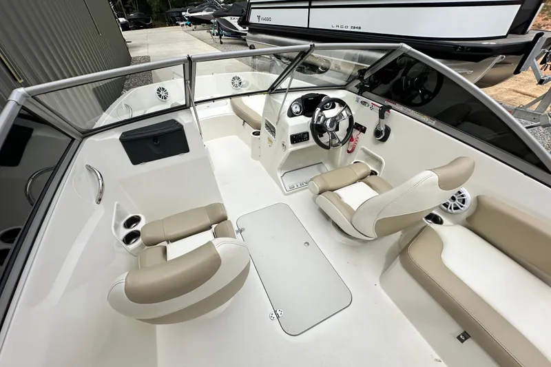 Slide: The Image of 2019 Stingray 191 DC boat interior with beige and white seating, steering wheel, and cup holders. - 16