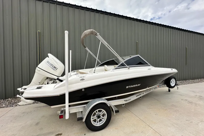 Slide: The Image of 2019 Stingray 191 DC boat with Suzuki outboard motor on trailer, parked outdoors. - 5
