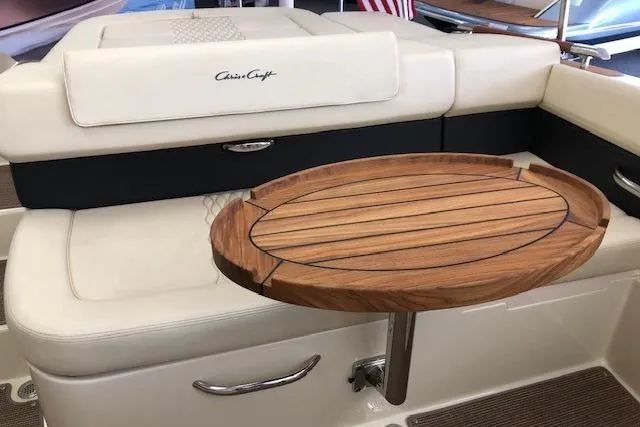 Slide: The Image of 2025 Chris-Craft Sportster 25 boat interior with wooden table and cushioned seating. - 16