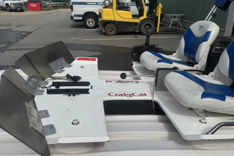Slide: The Image of 2009 CraigCat custom boat with blue and white seats, parked near industrial equipment. - 3