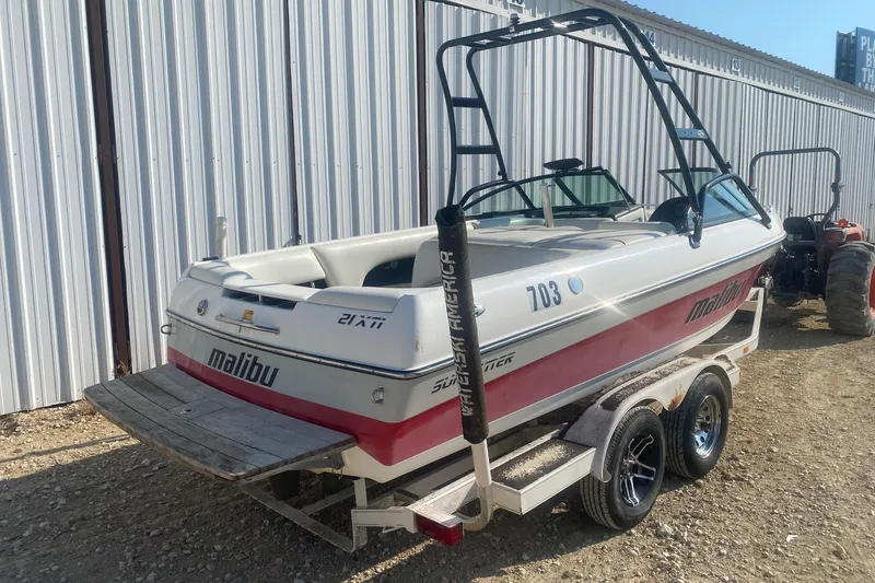 Slide: The Image of 2003 Malibu Sunsetter 21 XTi boat on trailer, parked beside a metal building. - 4