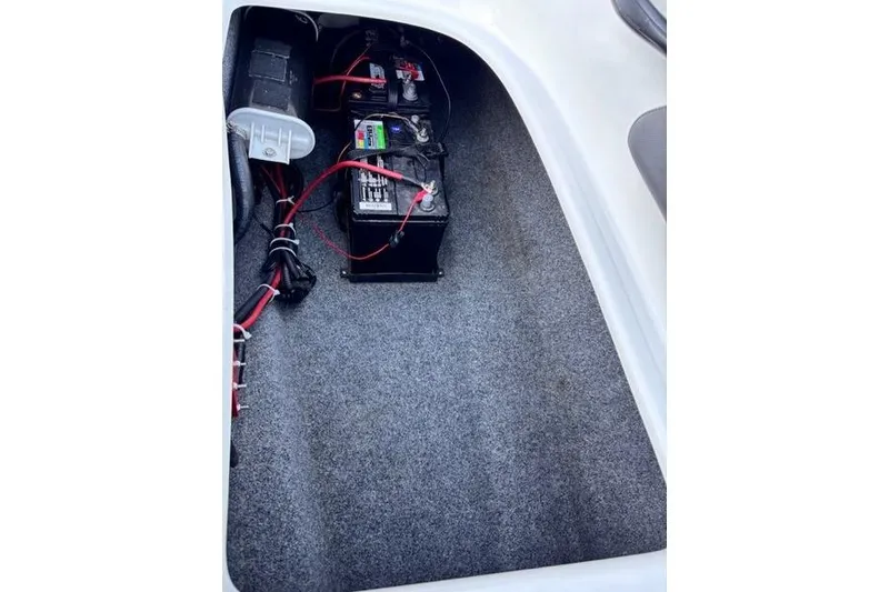 Slide: The Image of 2013 Yamaha AR192 boat battery compartment with wiring and carpeted interior. - 25