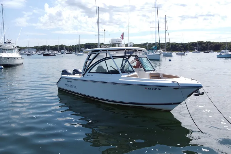 Slide: The Image of 2015 Pursuit DC 265 Dual Console boat docked in a marina with other vessels. - 1