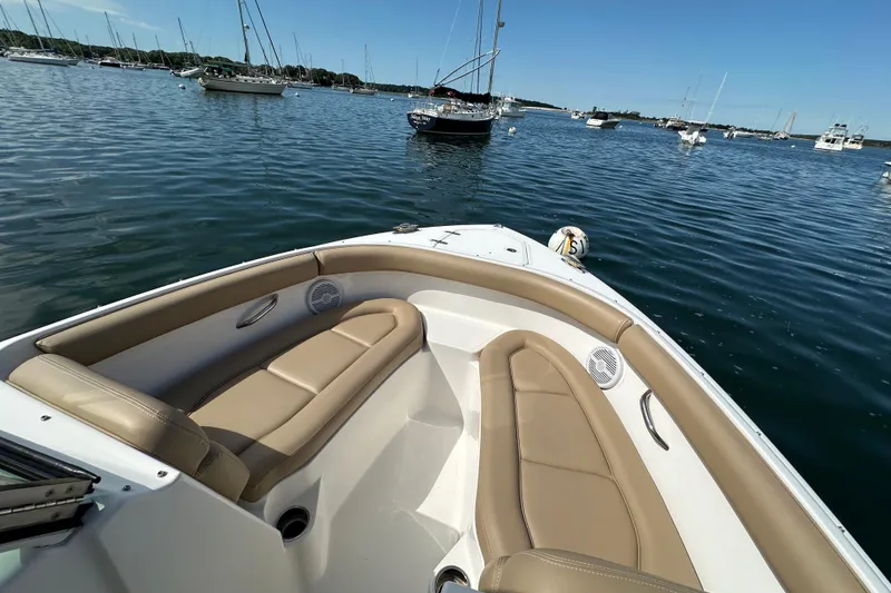 Slide: The Image of 2015 Pursuit DC 265 Dual Console boat with tan seating, anchored in a calm harbor. - 11