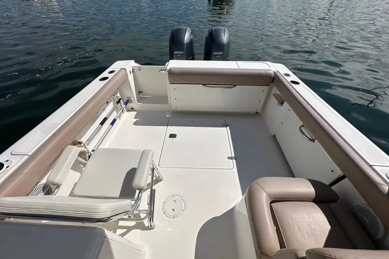 Slide: The Image of 2015 Pursuit DC 265 Dual Console boat interior with seating and twin engines on water. - 17