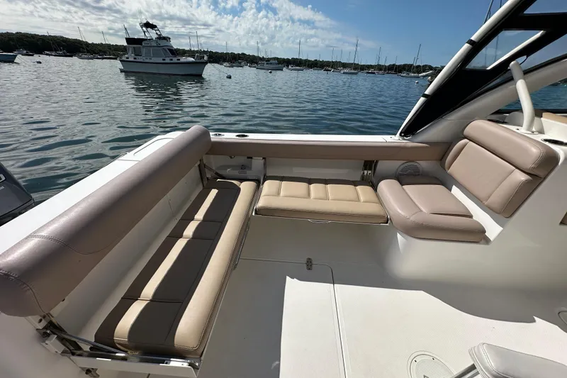 Slide: The Image of 2015 Pursuit DC 265 Dual Console boat interior with beige seating, docked on a sunny day. - 21