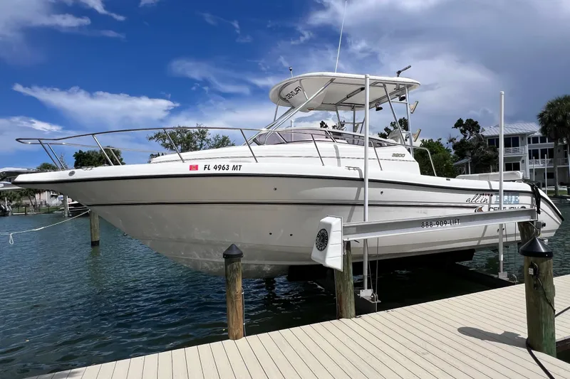 The Image of 2005 Century 3200 Walk-Around boat docked on a lift, clear sky background. - 0