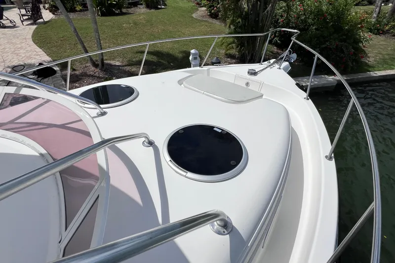 Slide: The Image of 2005 Century 3200 Walk-Around boat deck with hatches and railing, docked near lush greenery. - 22