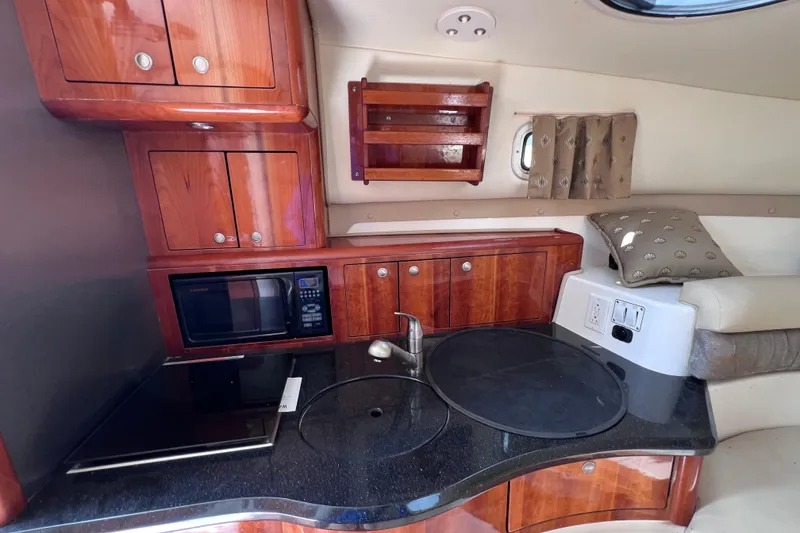 Slide: The Image of 2005 Century 3200 Walk-Around boat interior with kitchenette, microwave, and wooden cabinets. - 42