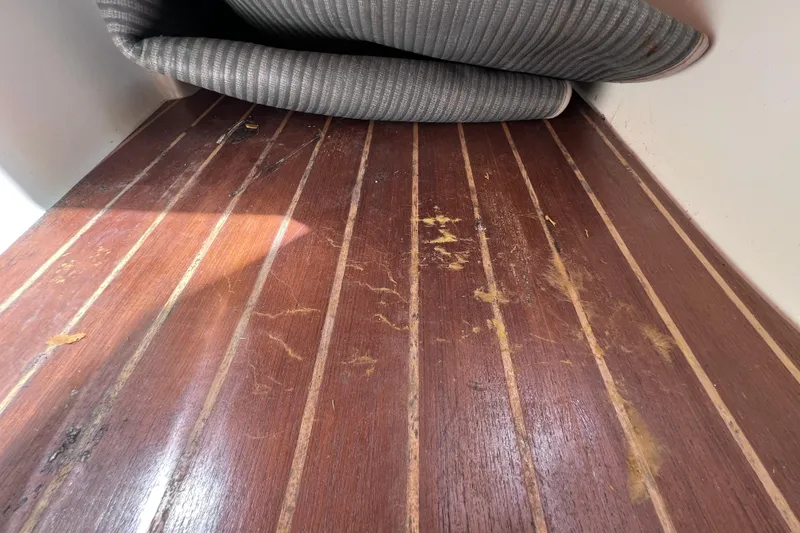 Slide: The Image of Worn wooden flooring on a 2005 Century 3200 Walk-Around boat, with rolled-up mat. - 50