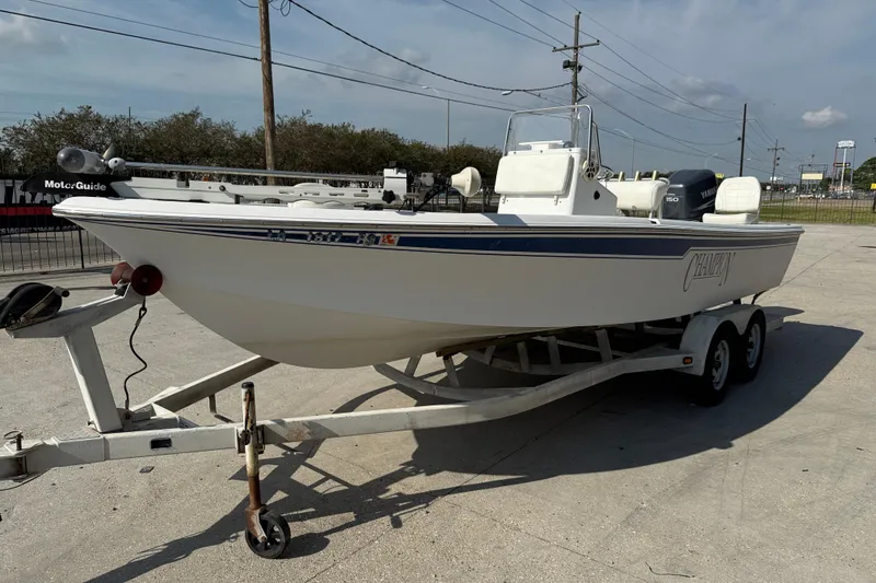 Slide: The Image of 2008 Champion 220 Bay boat on trailer, featuring a Yamaha motor, parked outdoors. - 4