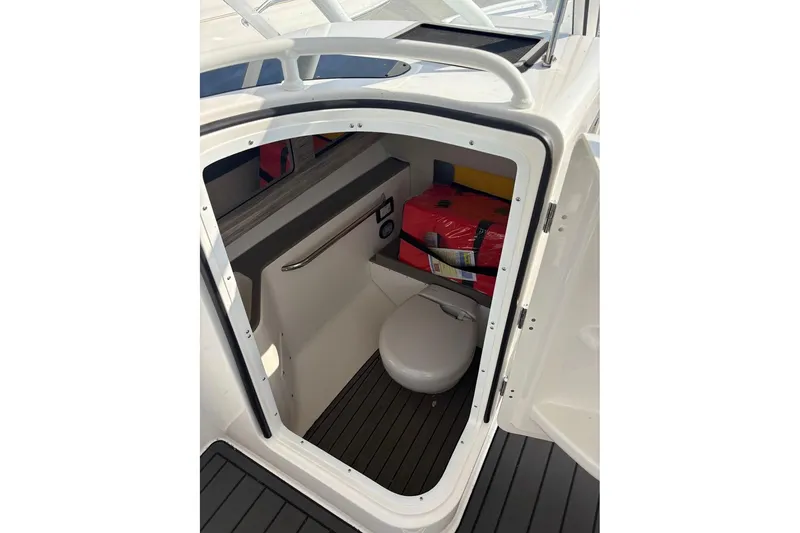 Slide: The Image of 2023 Edgewater 248 CX boat interior with compact restroom and storage area. - 19