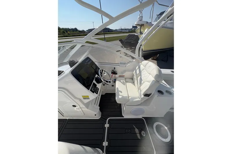 Slide: The Image of 2023 Edgewater 248 CX boat interior with helm, white seating, and modern controls. - 8