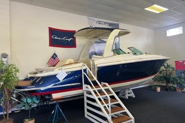 Slide: The Image of 2025 Chris-Craft Launch 28 GT boat displayed indoors with American flag. - 4