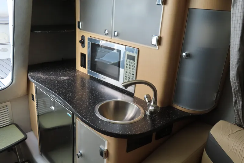 Slide: The Image of 2008 Baja 335 Performance boat interior with kitchenette, featuring sink, microwave, and storage cabinets. - 15