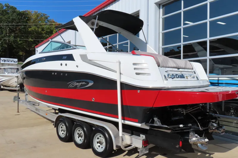 Slide: The Image of 2008 Baja 335 Performance boat on trailer, black and red design, parked outside a showroom. - 5
