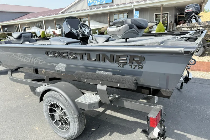 Slide: The Image of 2025 Crestliner XF 179 fishing boat on trailer, parked outside a marine store. - 1
