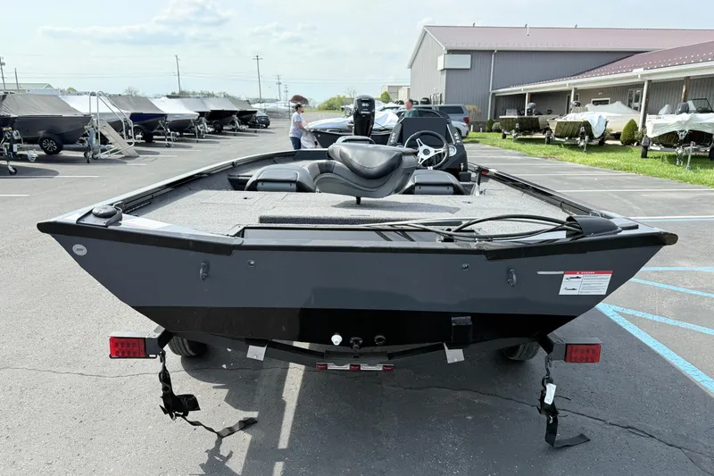 Slide: The Image of 2025 Crestliner XF 179 boat in parking lot, rear view, with trailers and buildings nearby. - 2