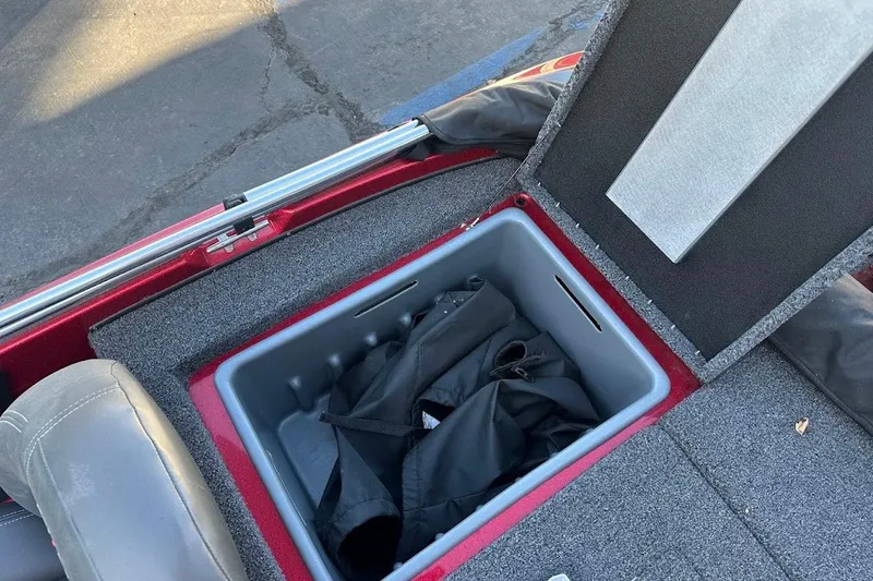 Slide: The Image of Open storage compartment in 2024 Nitro Z17 boat, featuring gray interior and black bag. - 28