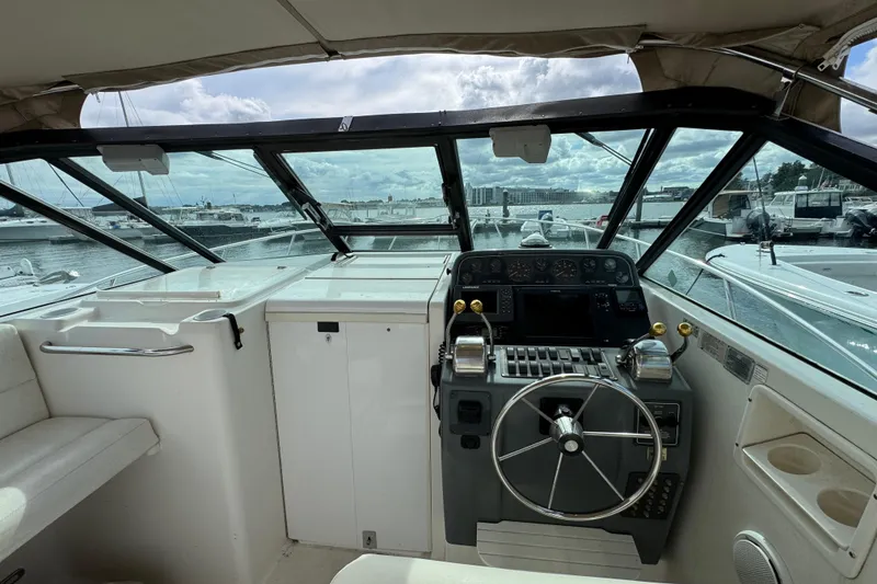 Slide: The Image of 1999 Tiara Yachts 2900 Open helm with marina view, featuring steering wheel and control panel. - 15