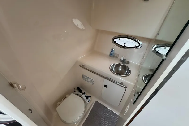 Slide: The Image of 1999 Tiara Yachts 2900 Open bathroom with sink, toilet, and porthole window. - 29
