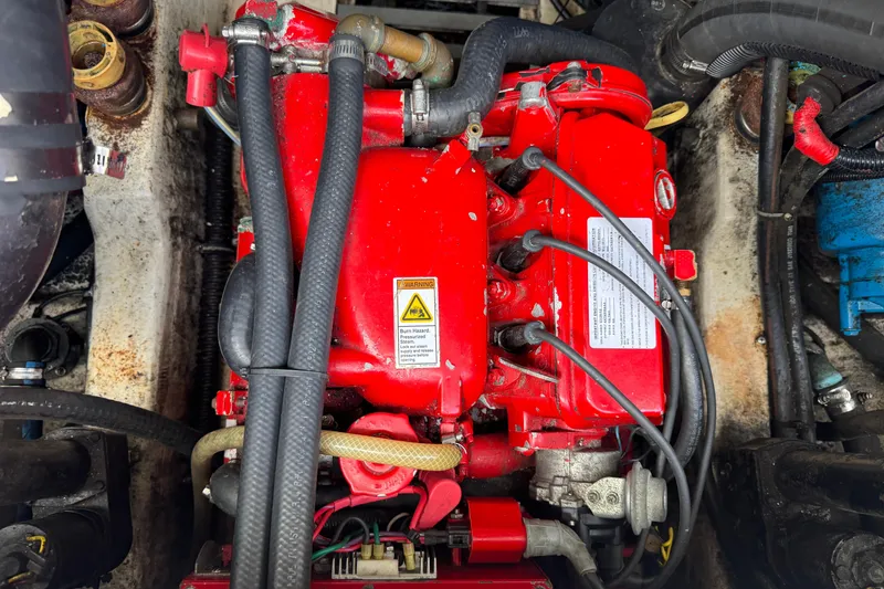 Slide: The Image of Engine compartment of a 1999 Tiara Yachts 2900 Open, featuring a red engine with hoses. - 35