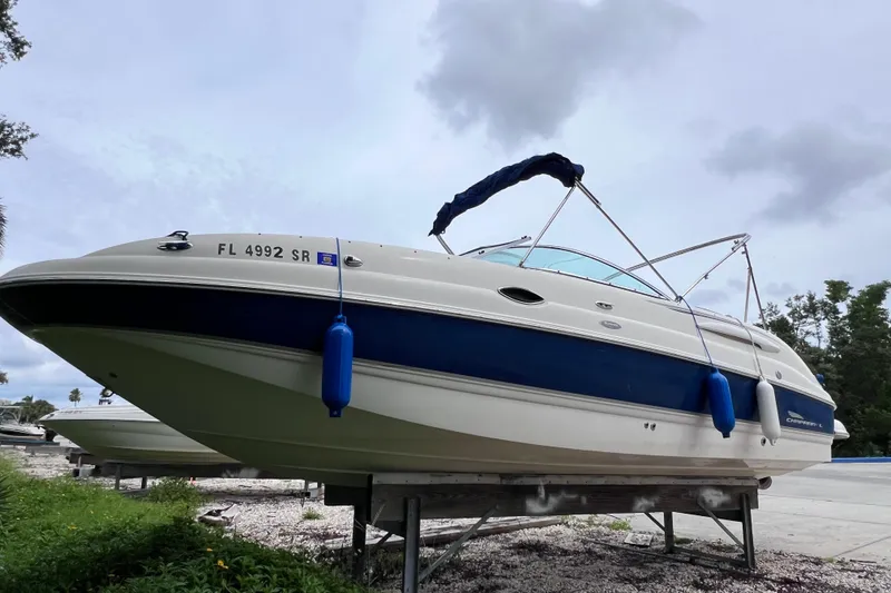 The Image of 2004 Chaparral Sunesta 254 boat on trailer, blue and white design, overcast sky. - 0
