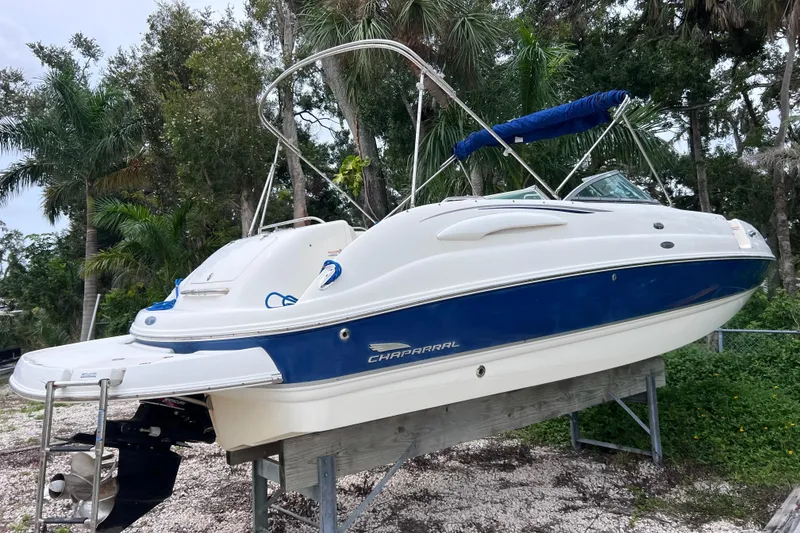 Slide: The Image of 2004 Chaparral Sunesta 254 boat on stand, surrounded by lush greenery. - 2