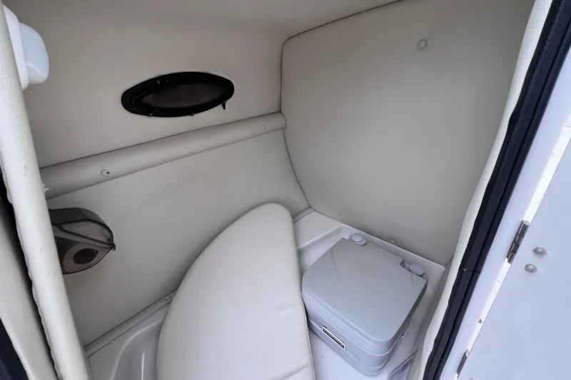 Slide: The Image of 2004 Chaparral Sunesta 254 boat interior with compact toilet and small window. - 30