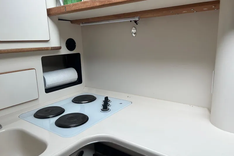 Slide: The Image of 1996 Sea Ray 370 Sedan Bridge kitchen with electric stove and storage shelves. - 10